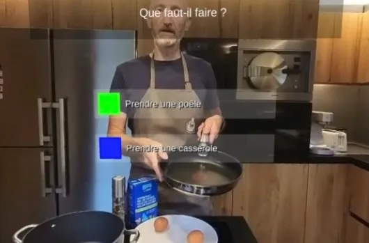 Image d'un jeu PERILUDUS : un homme tient une poêle dans une cuisine. La question « Que faut-il faire ? » s'affiche en haut, avec deux réponses possibles, « Prendre une poêle » et « Prendre une casserole ».